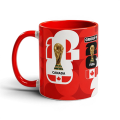 Fann Bliss red ceramic coffee mug featuring FIFA World Cup trophy, Canadian flag, and Group B soccer graphics.